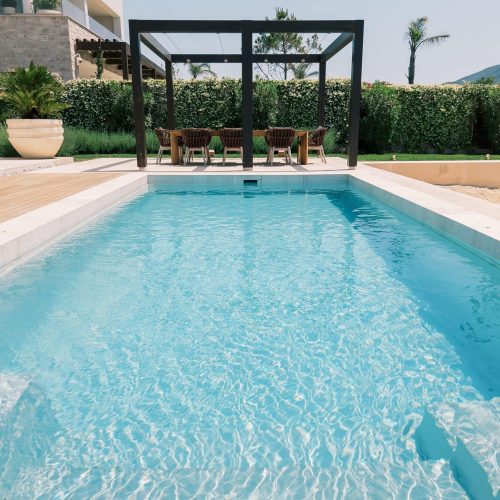 Long table with chairs in a wooden gazebo by the pool near a modern hotel. High quality photo